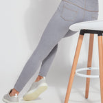 color=Uptown Grey, Seated rear view of uptown gray  toothpick denim jean leggings with patented concealed waistband